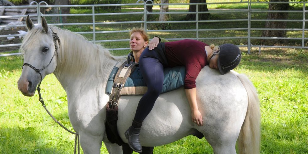 Eine Frau entspannt ihren Rücken auf dem Pferd