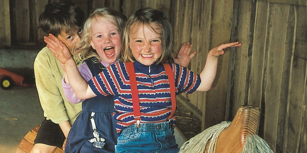 Fröhliche Kinder auf einem Holzpferd.